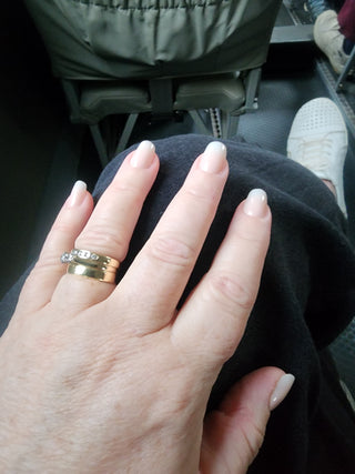 Hand with a ring on a black surface, possibly in a vehicle.
