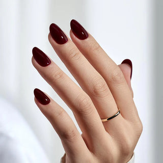 Hand with dark red nail polish on a white background