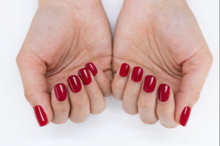 Two hands with red nail polish on a white background