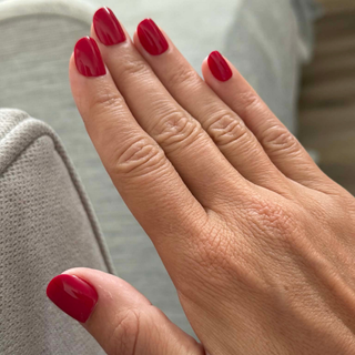 Close-up of a hand with red press-on nails on a neutral background