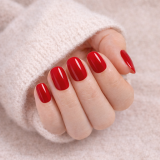 Hand with red press-on nails on a soft beige background