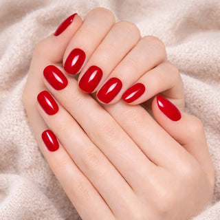 Close-up of hands with red press-on nail on a soft beige background