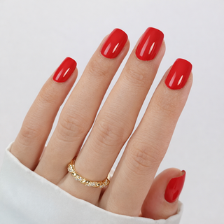 Hand with red press-on nails and a gold ring on a white background