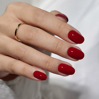 Hand with red nail polish on a blurred white background
