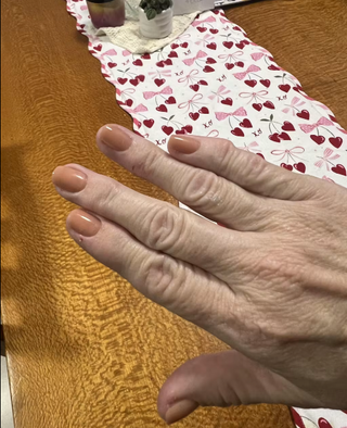 Hand on a wooden surface with a patterned fabric in the background