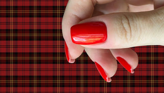 Hand with red nail polish on a red plaid background