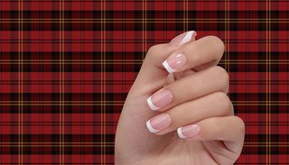 French Manicure Press-on Nails on a woman's hand, with a red tartan background