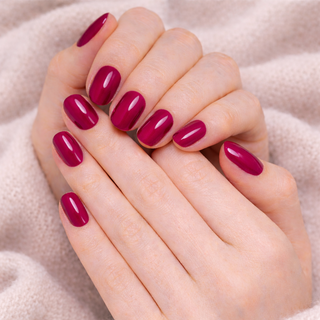 Close-up of hands with cherry press-on nails on a soft beige background