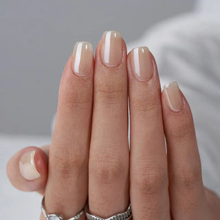 Close-up of a hand with beige nail polish on a neutral background