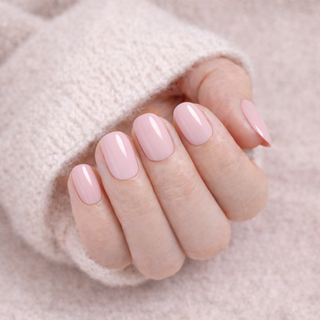 Close-up of a hand with pink press-on nails on a soft cream background