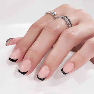 Hand with pink nails and black tips wearing two rings on a white background