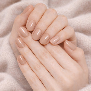 Close-up of hands with beige press-on nails on a soft beige background