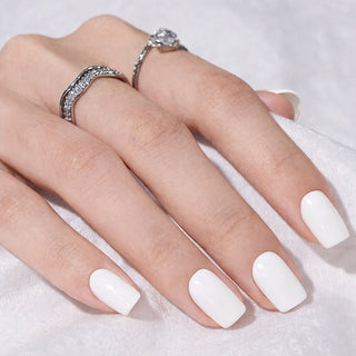 Hand with white press-on nails and silver rings on a light background