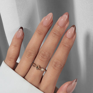 Hand with pink nail polish and a ring on a neutral background