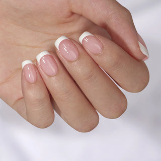 Close-up of a hand with pink nail polish and white tips on a light background