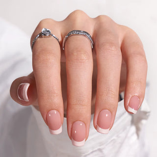 Hand with pink nail polish and silver rings on a white background