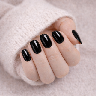 Hand with black press-on nails on a soft soft  background