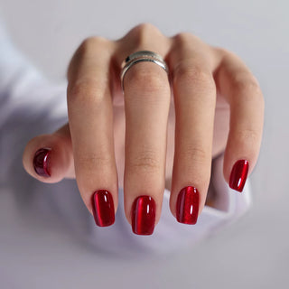 Hand with red nail polish on a plain background