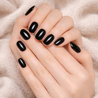 Hand with black press-on nails on a beige fabric background