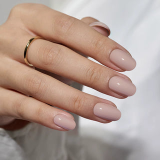 Close-up of a hand with pink nail polish and a gold ring on a blurred background