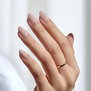 Hand with pink nail polish and a gold ring on a light background