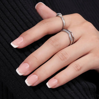 Hand wearing two silver rings with a black background