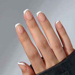 Close-up of a hand with nails painted in a neutral color with white tips on a gray background
